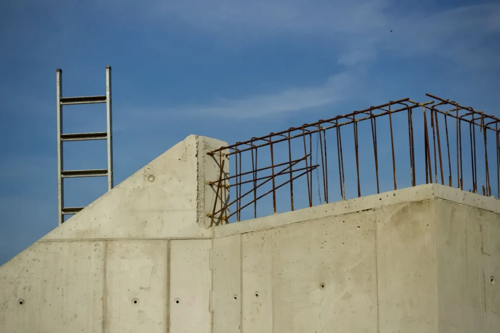 קיר בטון מזוין בבנייה עם ברזלי זיון וסולם — המחשה לבניית ממ"ד